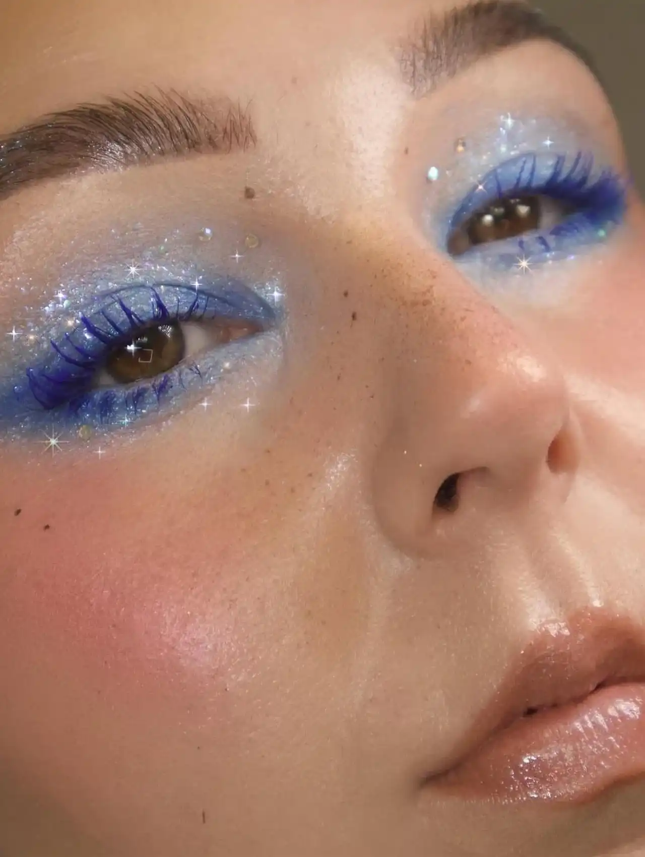 Mujer con sombras brillantes y delineador de ojos azul, estilo glamuroso.