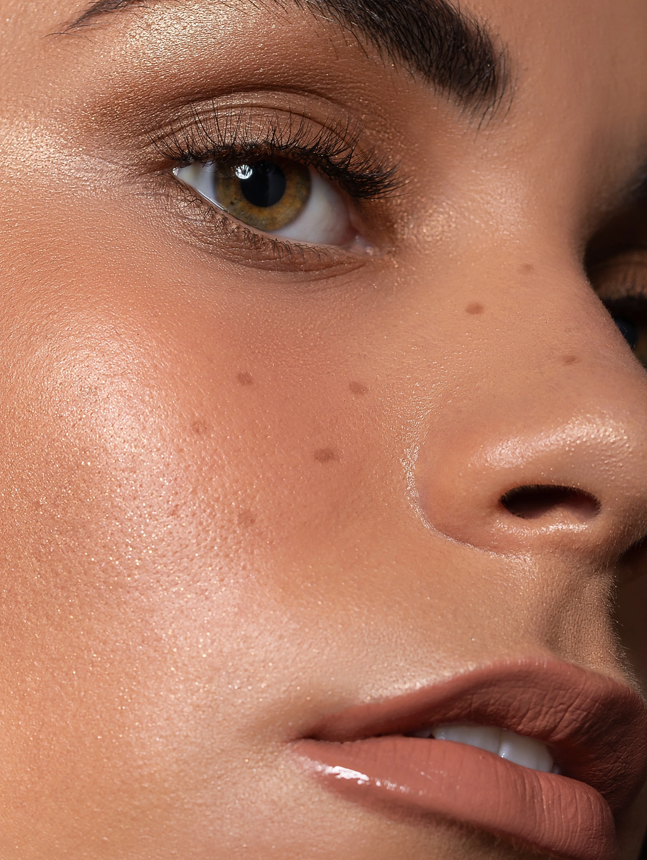 Macro close-up of glowing skin with soft bronze tones — minimalist Thanksgiving makeup for a radiant finish.