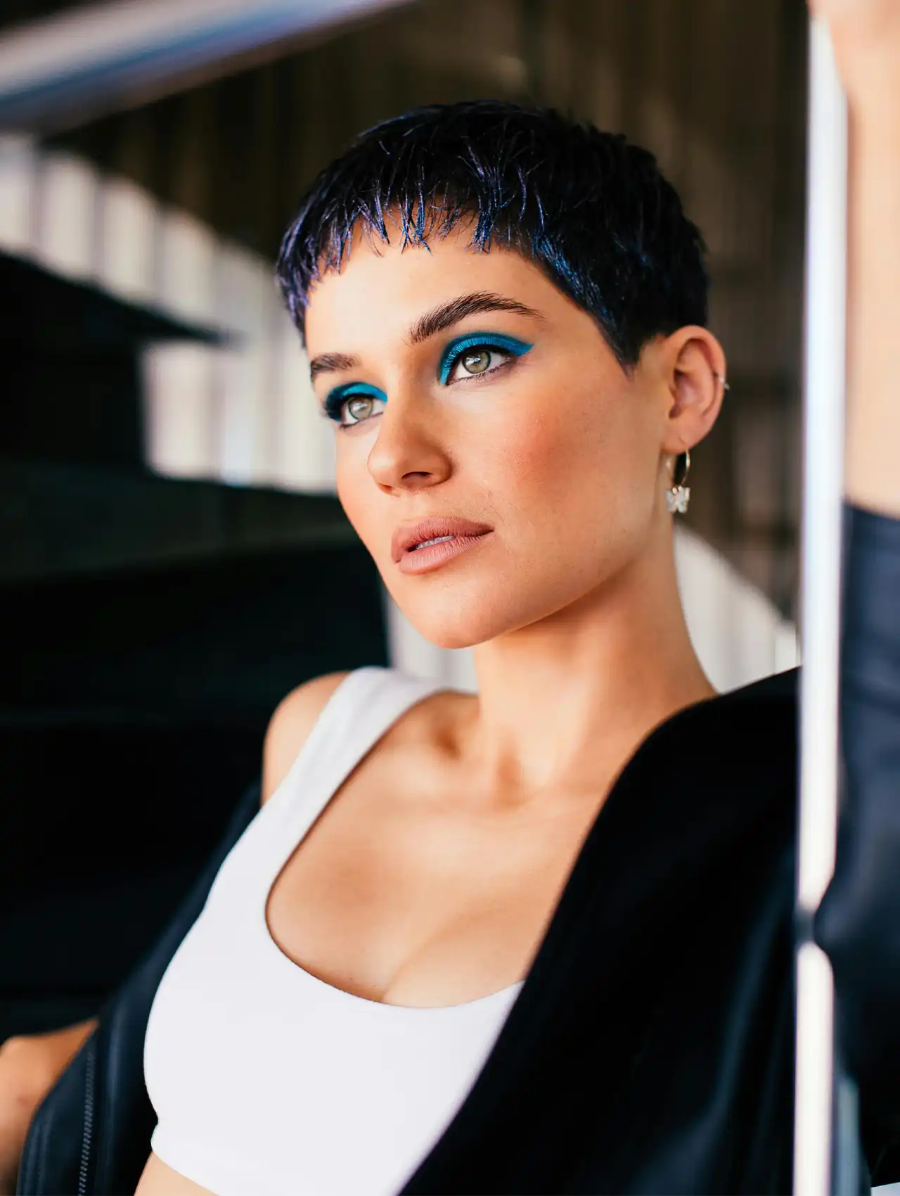 Mujer con corte de cabello corto y delineador de ojos azul intenso con sombras a juego.