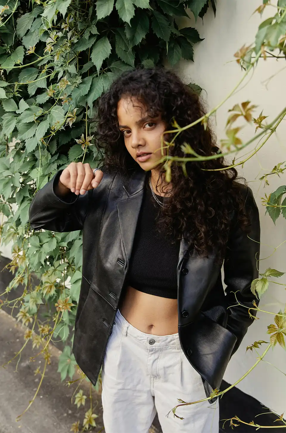 Woman wearing a black leather blazer styled with casual jeans and crop top for fall fashion