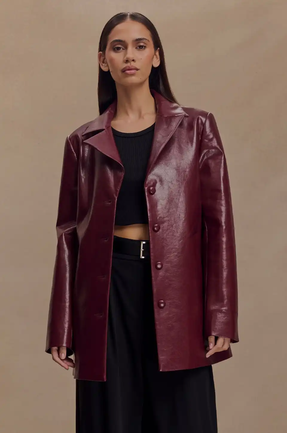 Woman wearing a burgundy leather blazer styled with black wide-leg pants and crop top