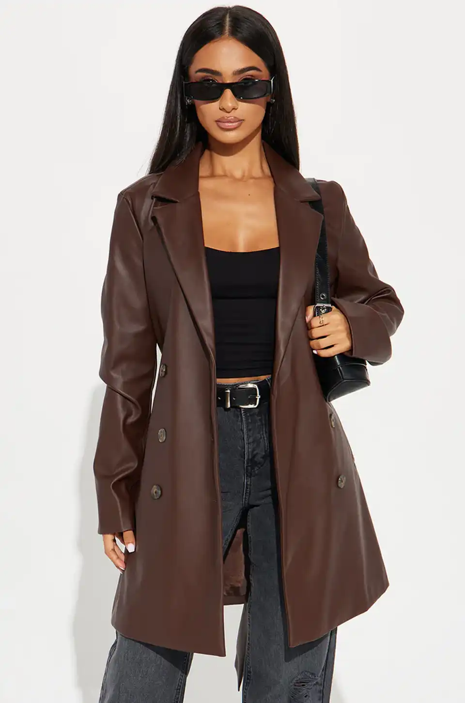Woman styled in a longline brown leather blazer with black crop top and jeans