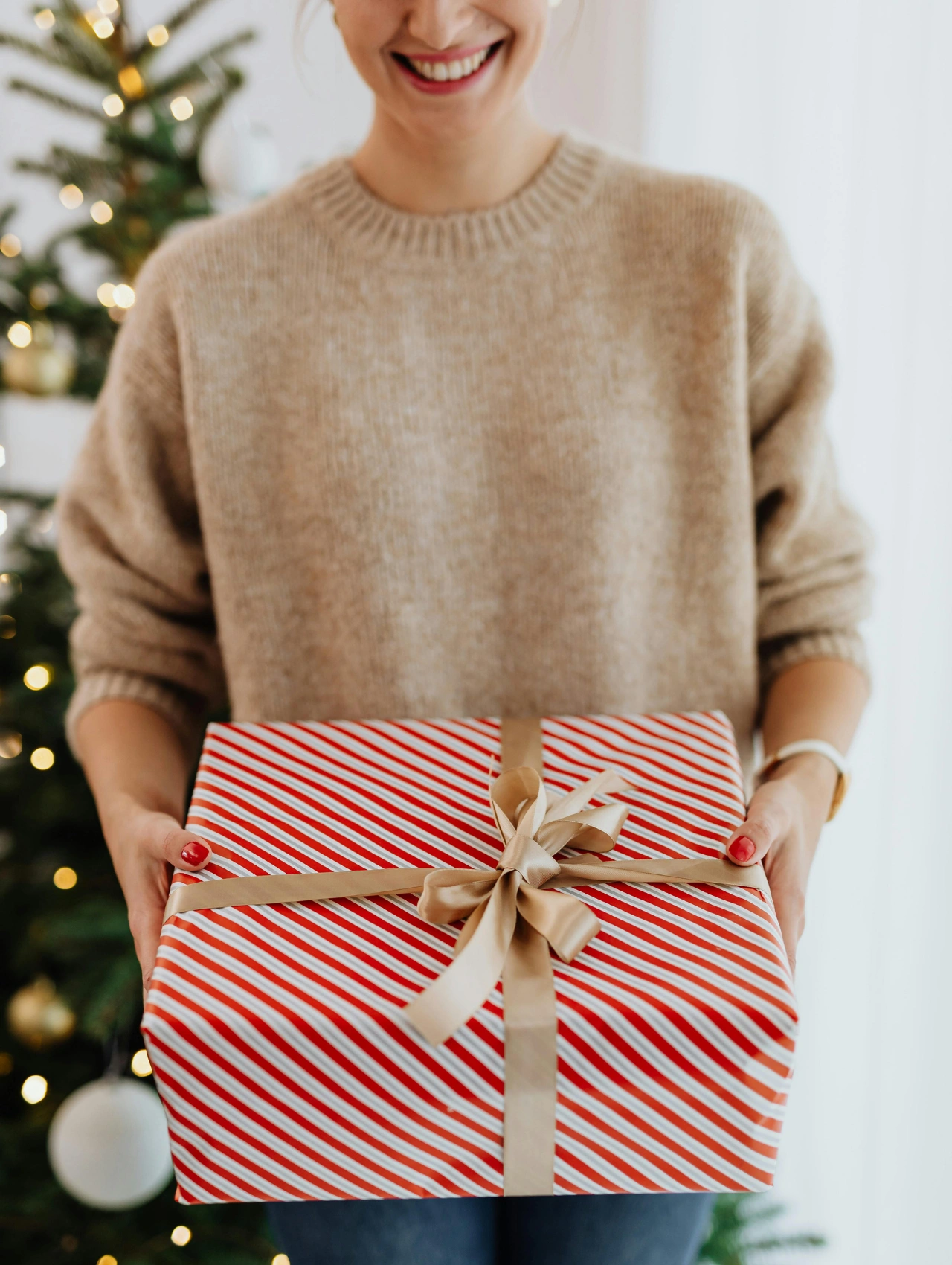 Woman holding a wrapped holiday present with festive red and white stripes, perfect for Last Minute Christmas Gifts inspiration