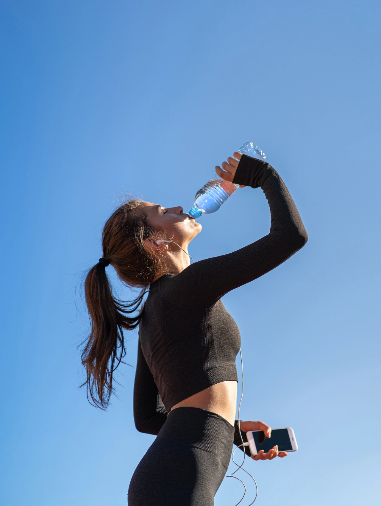 Athletic woman drinking water during exercise, rehydrating after a Christmas workout.