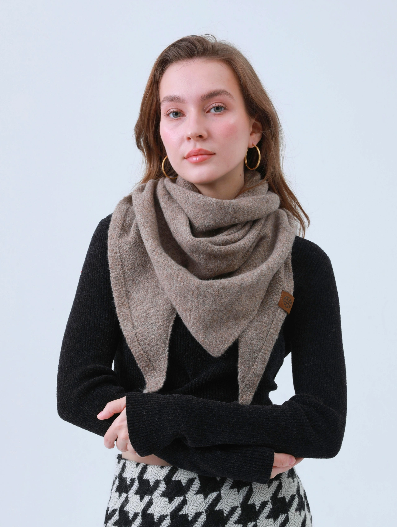 Woman wearing a cozy scarf with a fitted black sweater and houndstooth skirt, representing elegant and sexy winter outfits.