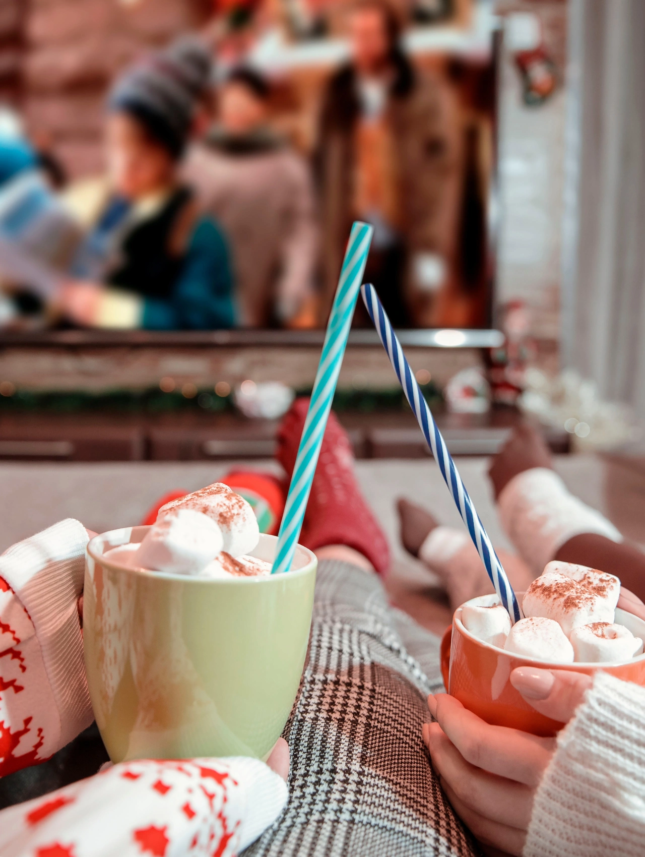 Two people relaxing with hot cocoa while watching a holiday film, perfect for highlighting must-see New Christmas Movies