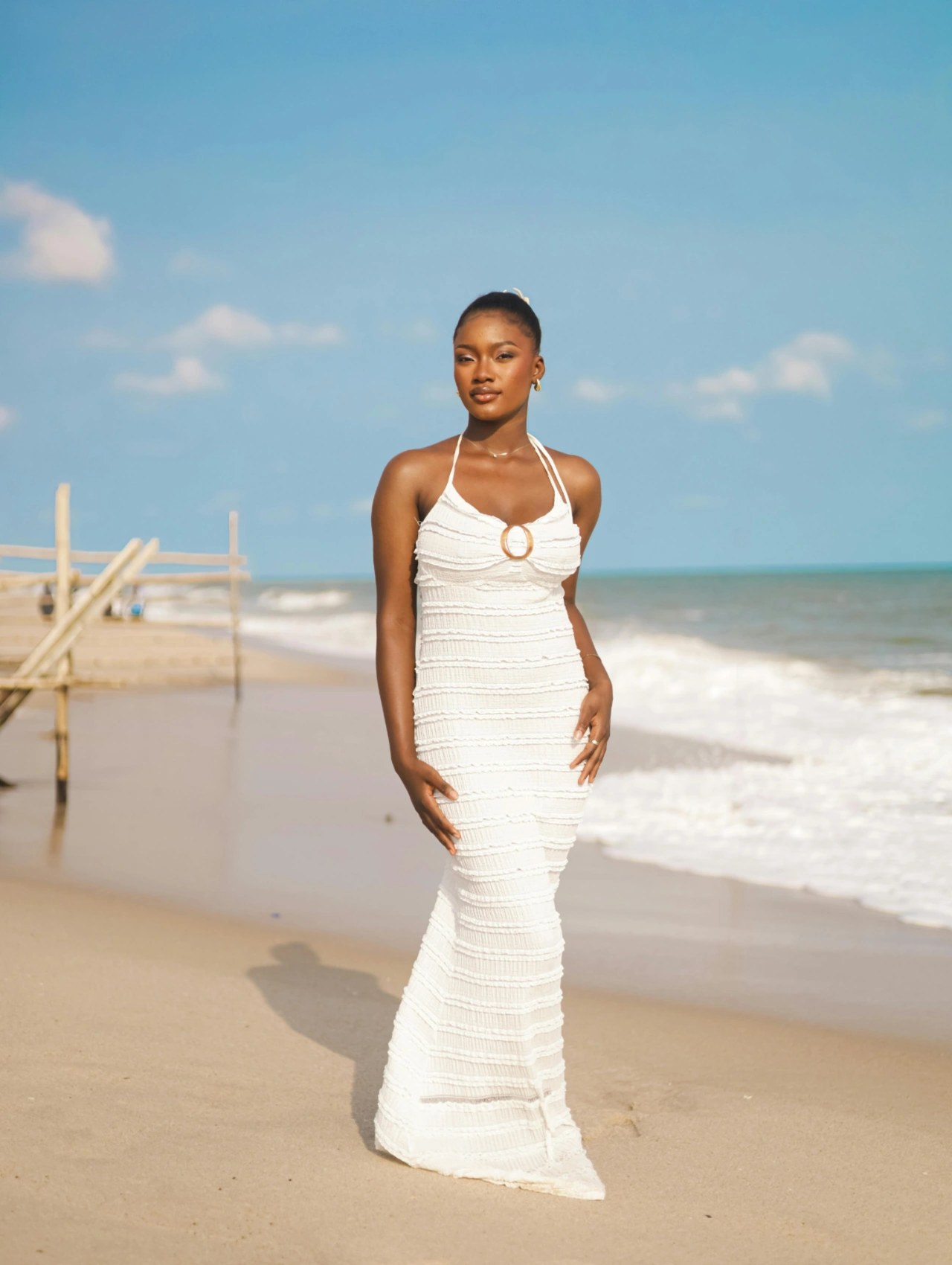 Spring clothing for women final words, elegant woman in a white textured maxi dress standing on the beach, showcasing spring clothing for women in a breezy coastal setting.