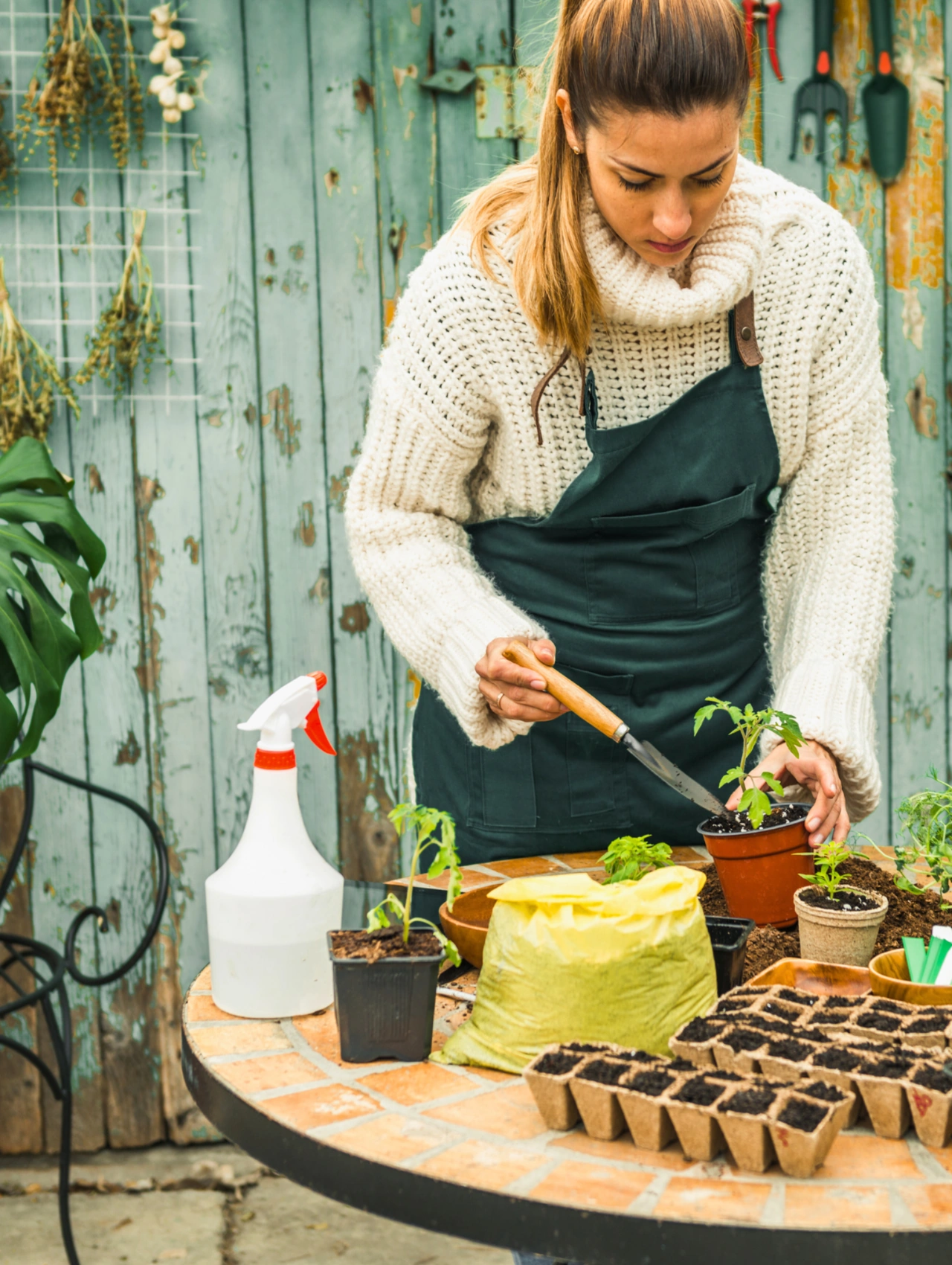 Maintain Your Garden, Yellow Spring Flowers and young seedlings being planted by a gardener at a table with tools, soil, and pots.