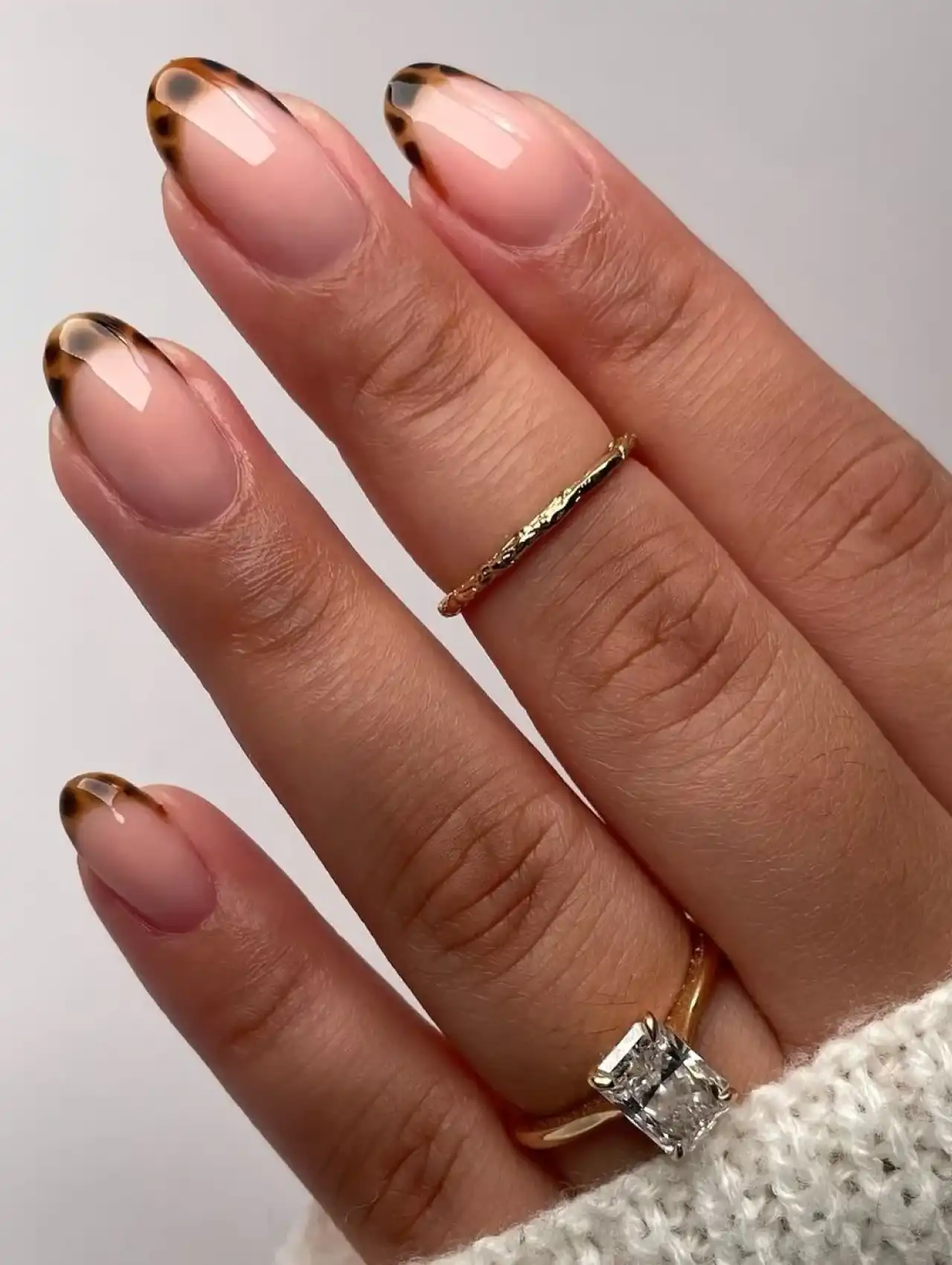 Close-up of almond-shaped nails with animal print French tips, showcasing nail art design 2025.