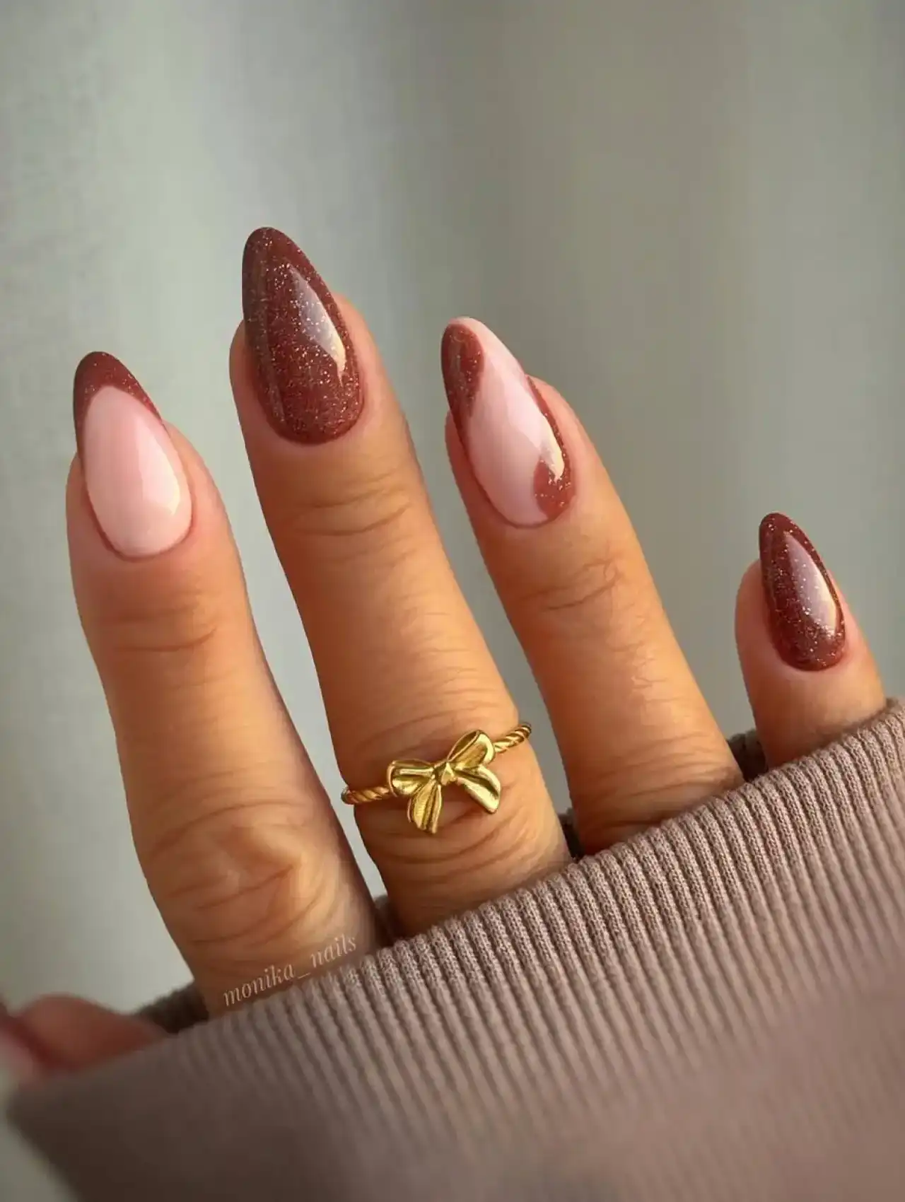 Almond-shaped nails with brown glitter French tips, highlighting nail art design 2025.