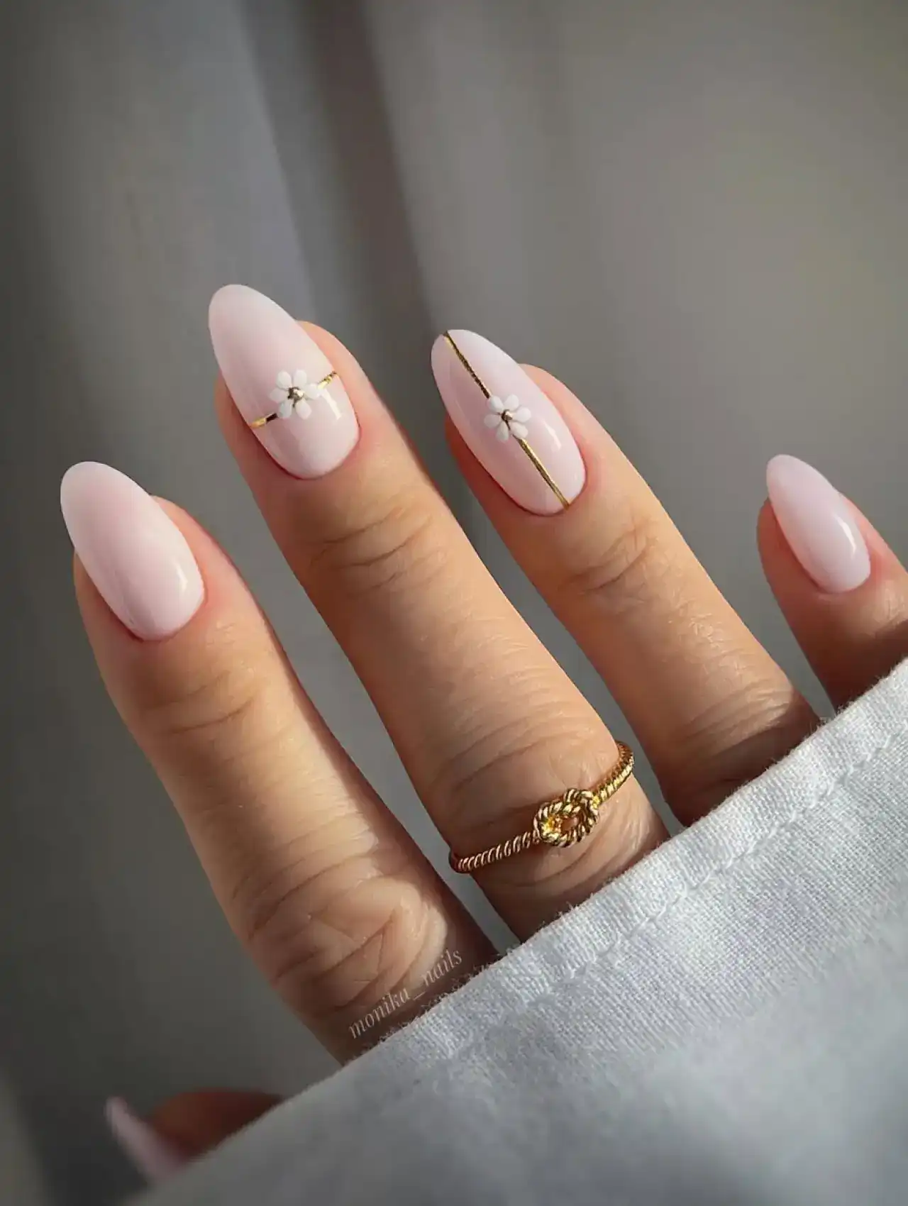 Light pink nails with delicate daisy and gold line accents, nail art design 2025.