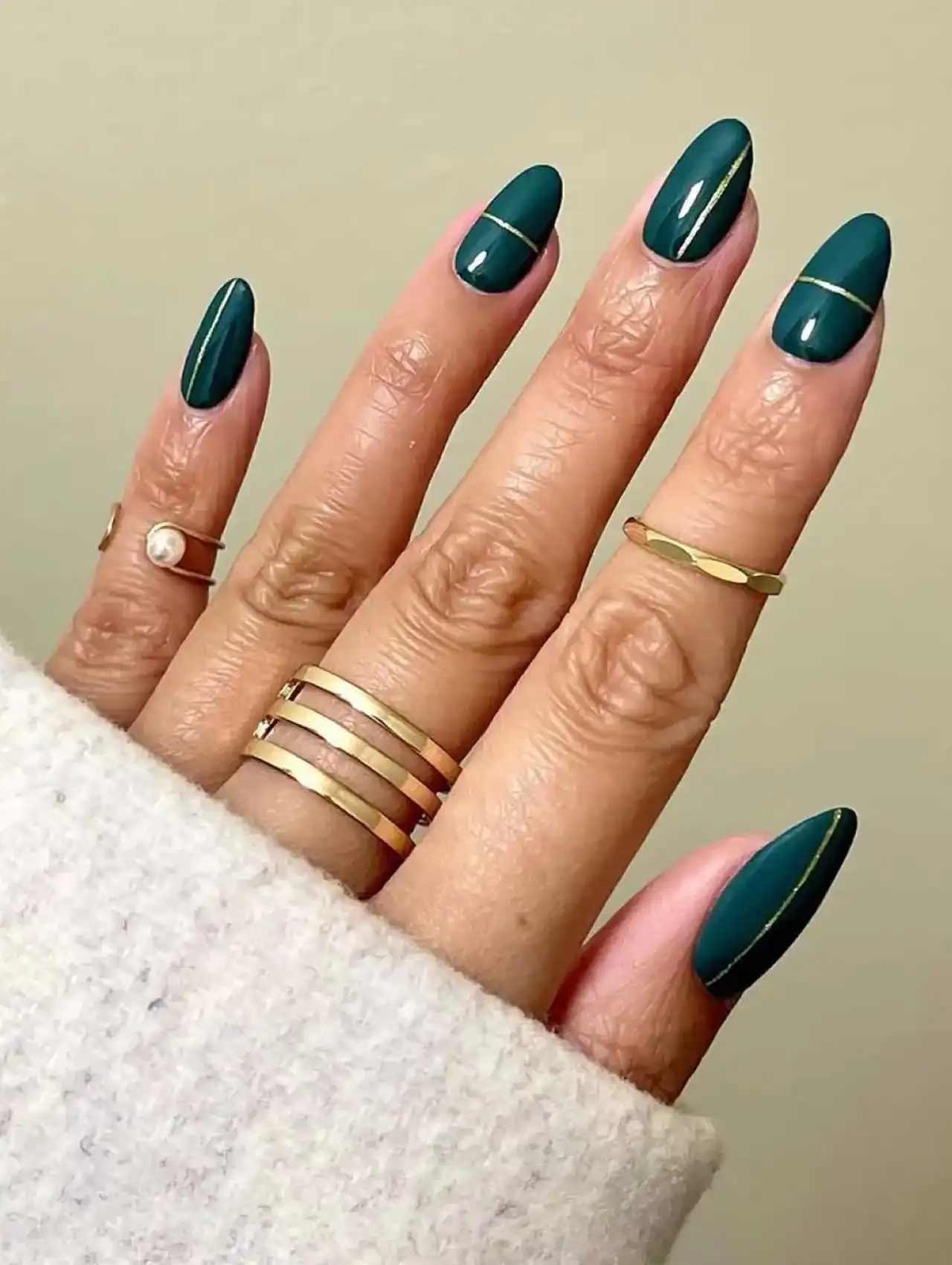 Deep emerald green nails with gold line accents, part of nail art design 2025.