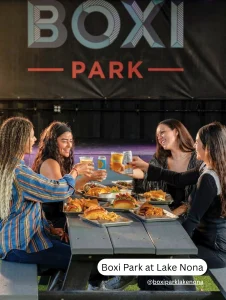 Group of women enjoying food and drinks at Boxi Park, a large pet friendly outdoor dining venue in Lake Nona.