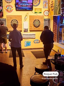 Dartboard wall and patrons at Roque Pub, one of Orlando’s pet friendly restaurants with an inviting local bar atmosphere.