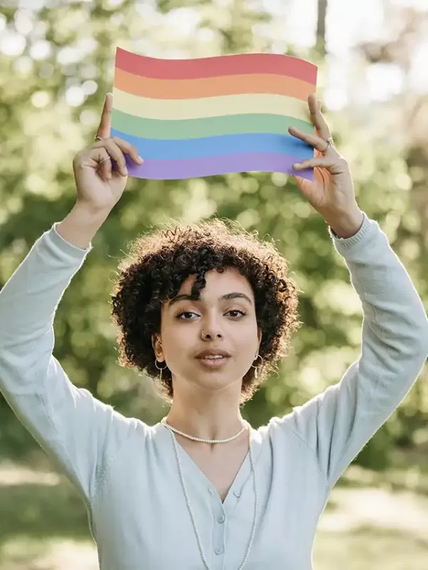 a woman holding up a rainbow flag
