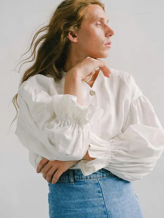 a woman with long hair wearing a white shirt and blue jeans