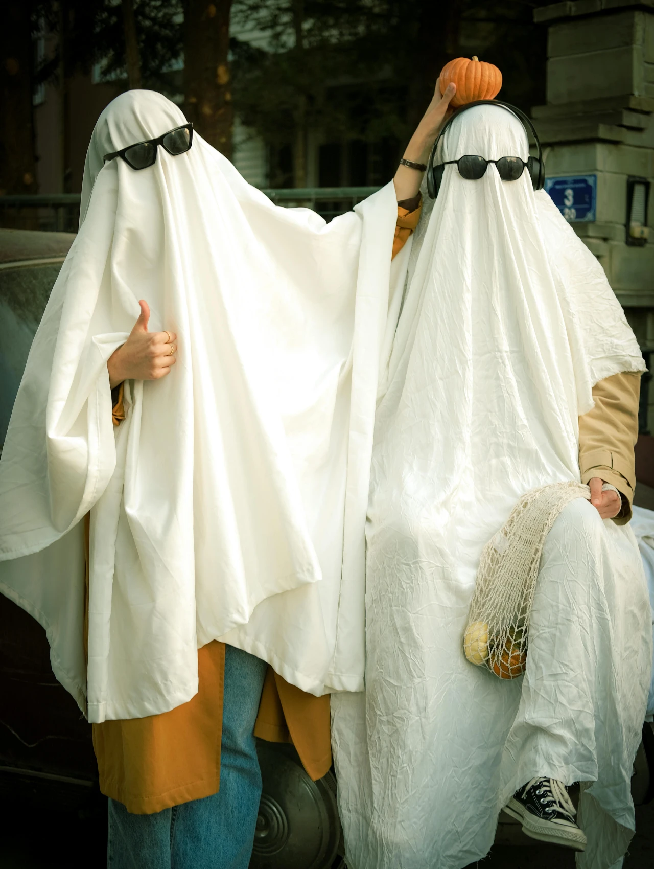 Pareja con disfraces para Halloween de fantasmas usando sábanas blancas y gafas de sol.