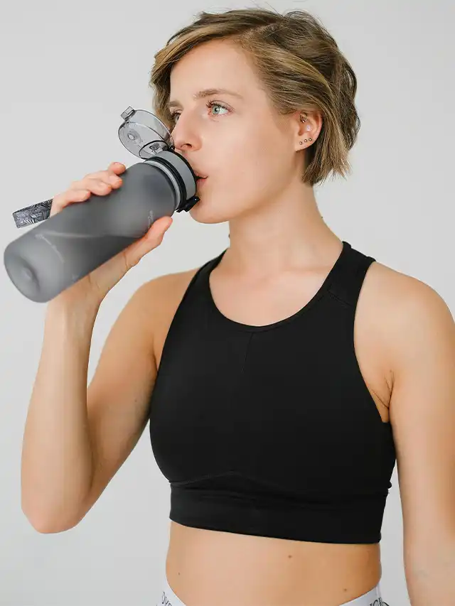 a woman drinking from a water bottle