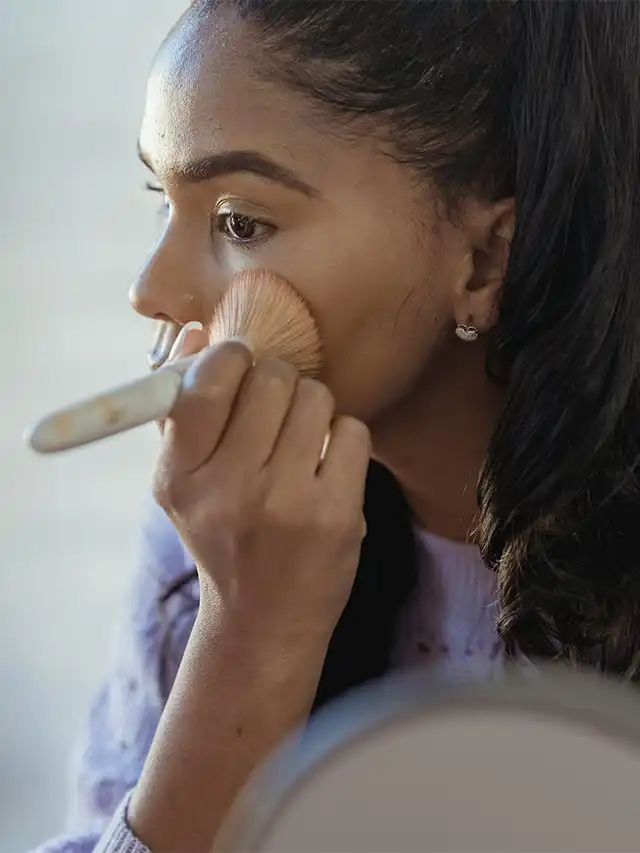 a woman applying makeup with a brush