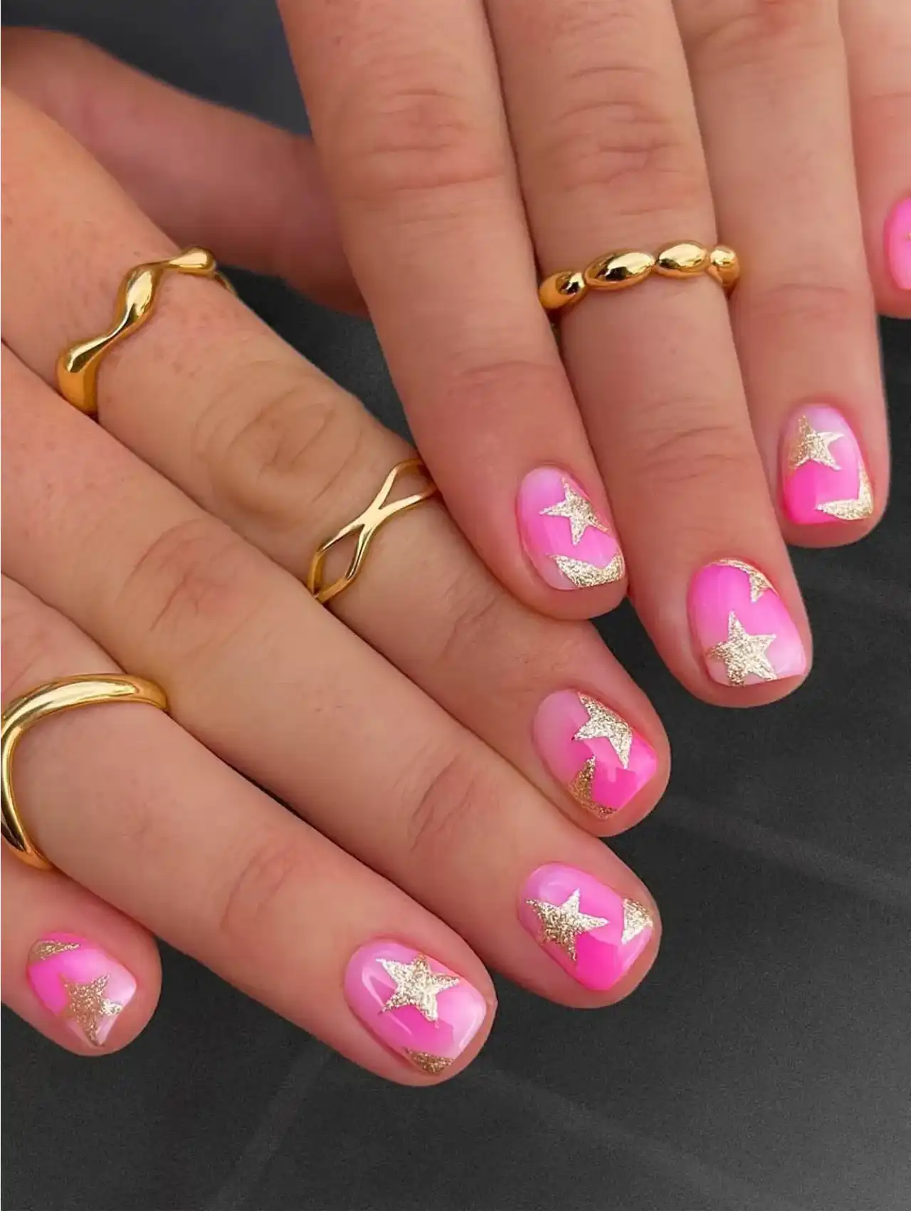 Neon pink nails with gold glitter star accents