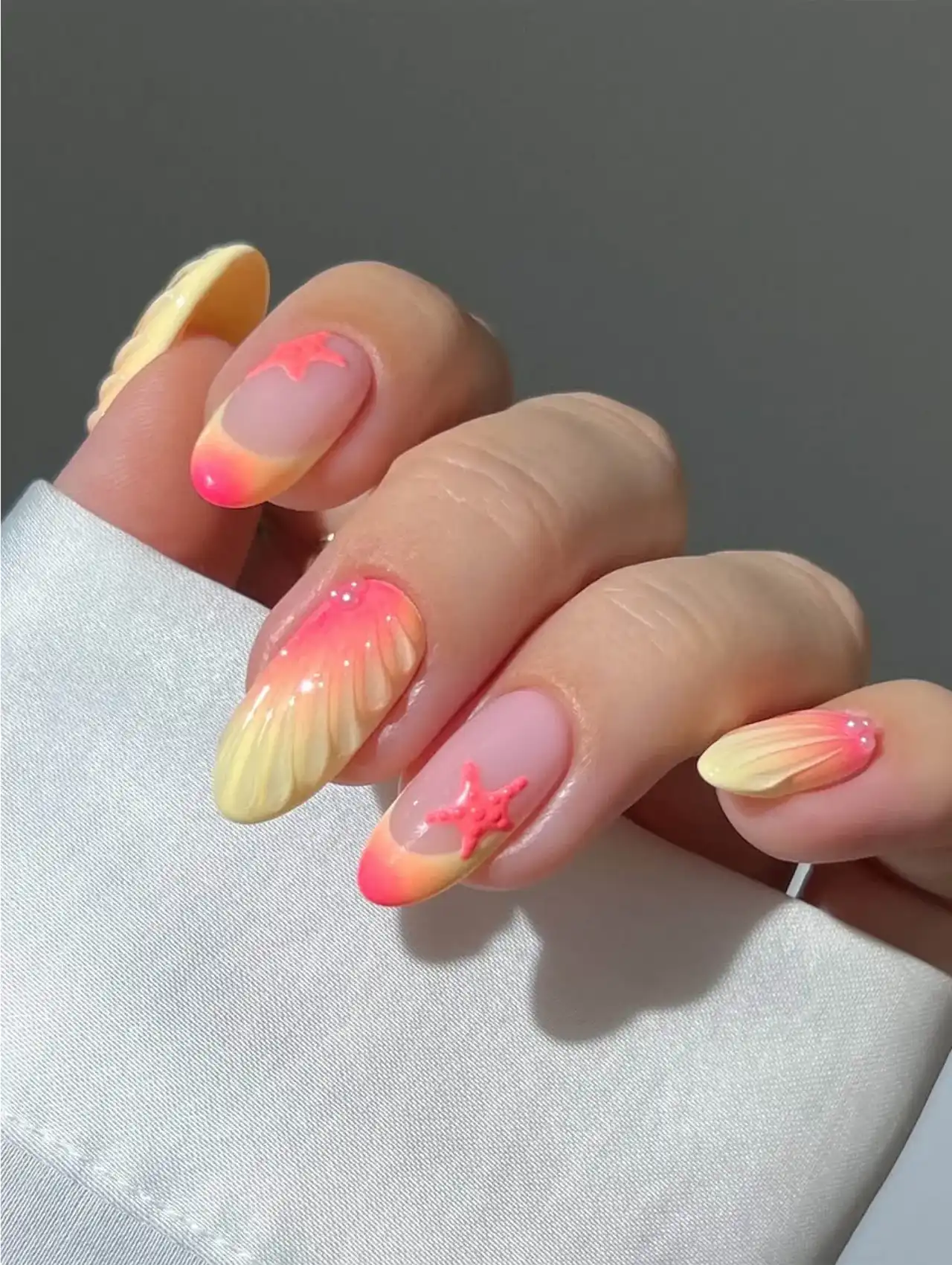 Neon nails with starfish and seashell-inspired 3D art in pink and yellow