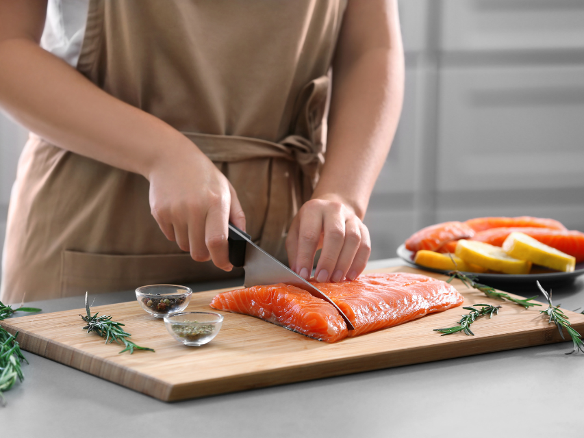 a person cutting a piece of salmon