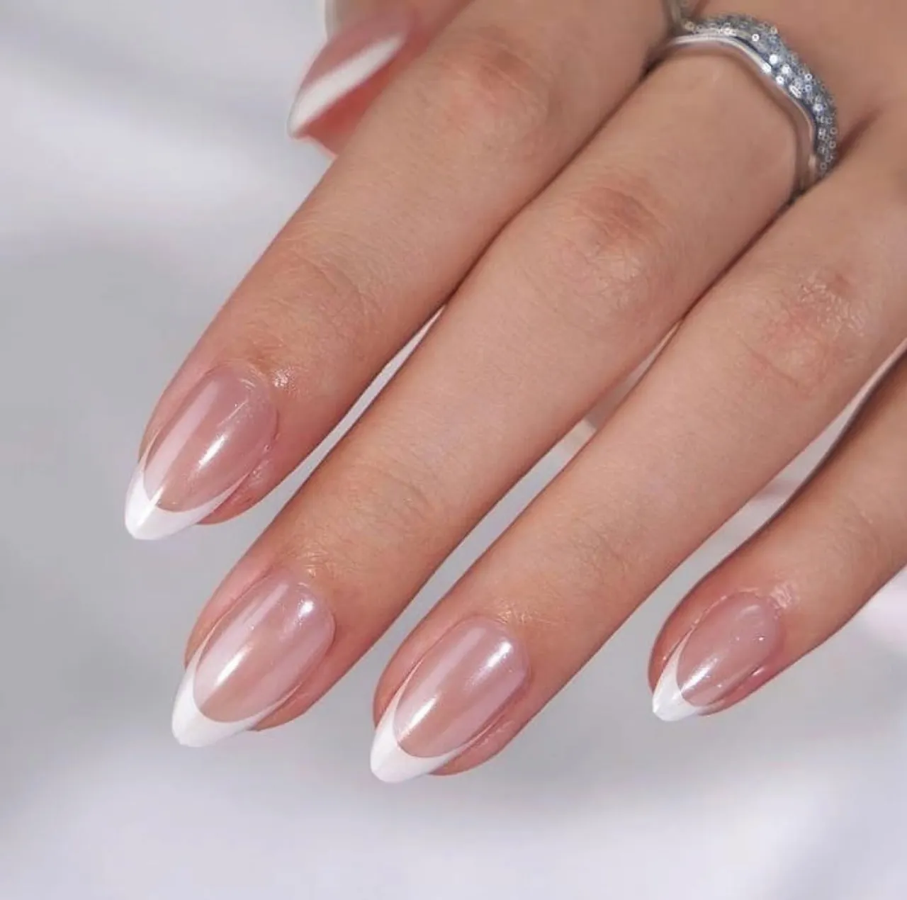 Diseños de uñas acrílicas francesas perladas con acabado brillante y forma almendrada