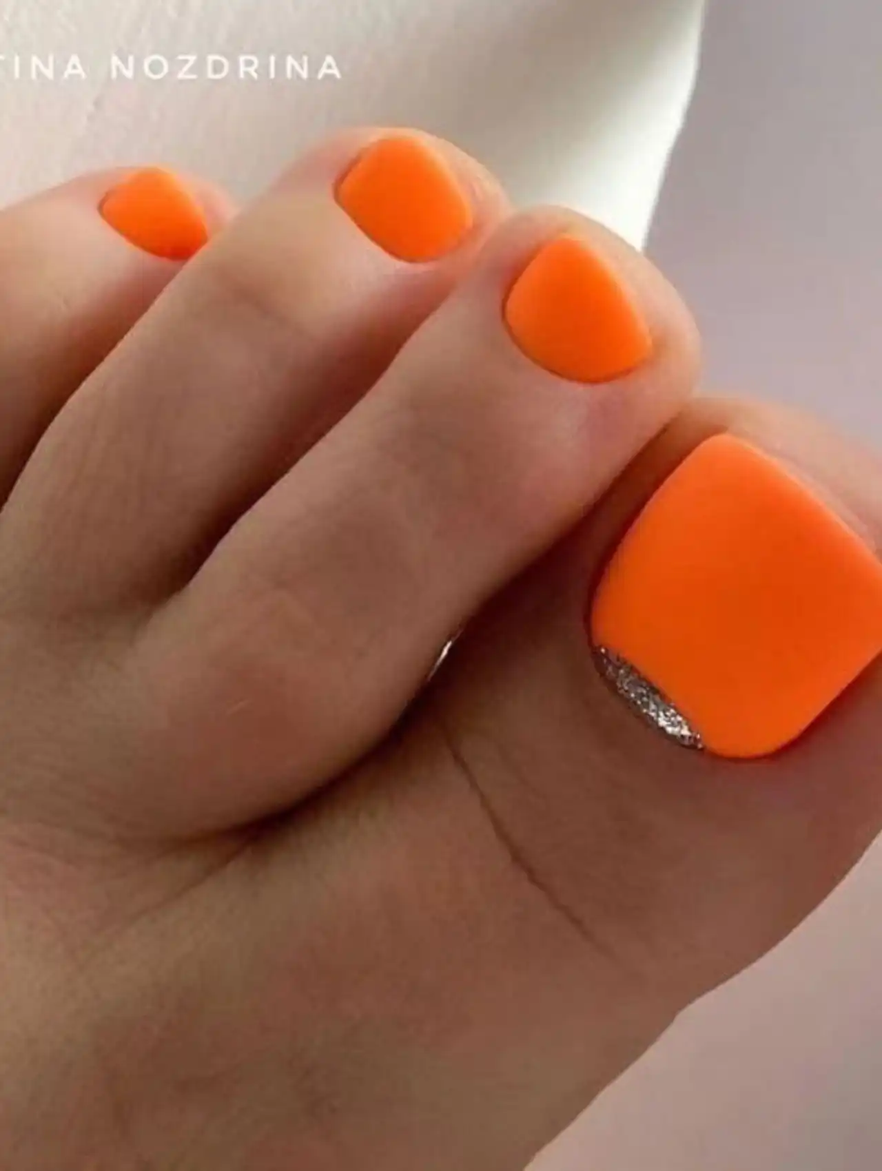 Bright orange summer toe nail design with silver accent detail
