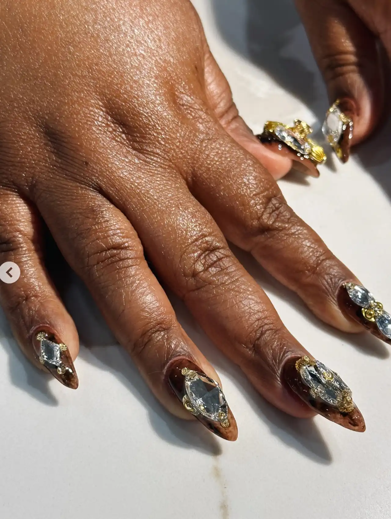 Da’Vine Joy Randolph showing golden gem-encrusted celebrity nails