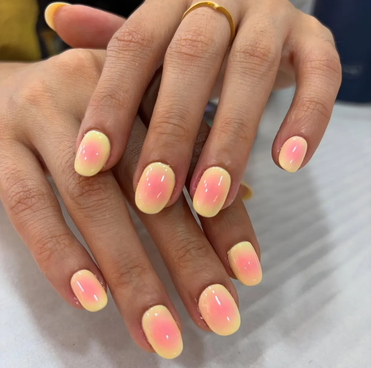 Diseño de uñas con efecto aerografía en tonos pastel rosado y amarillo.