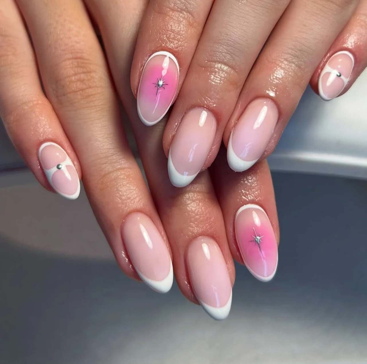 Diseño de uñas aura francesa con base nude, detalles blancos y decoración rosa en estilo aura.
