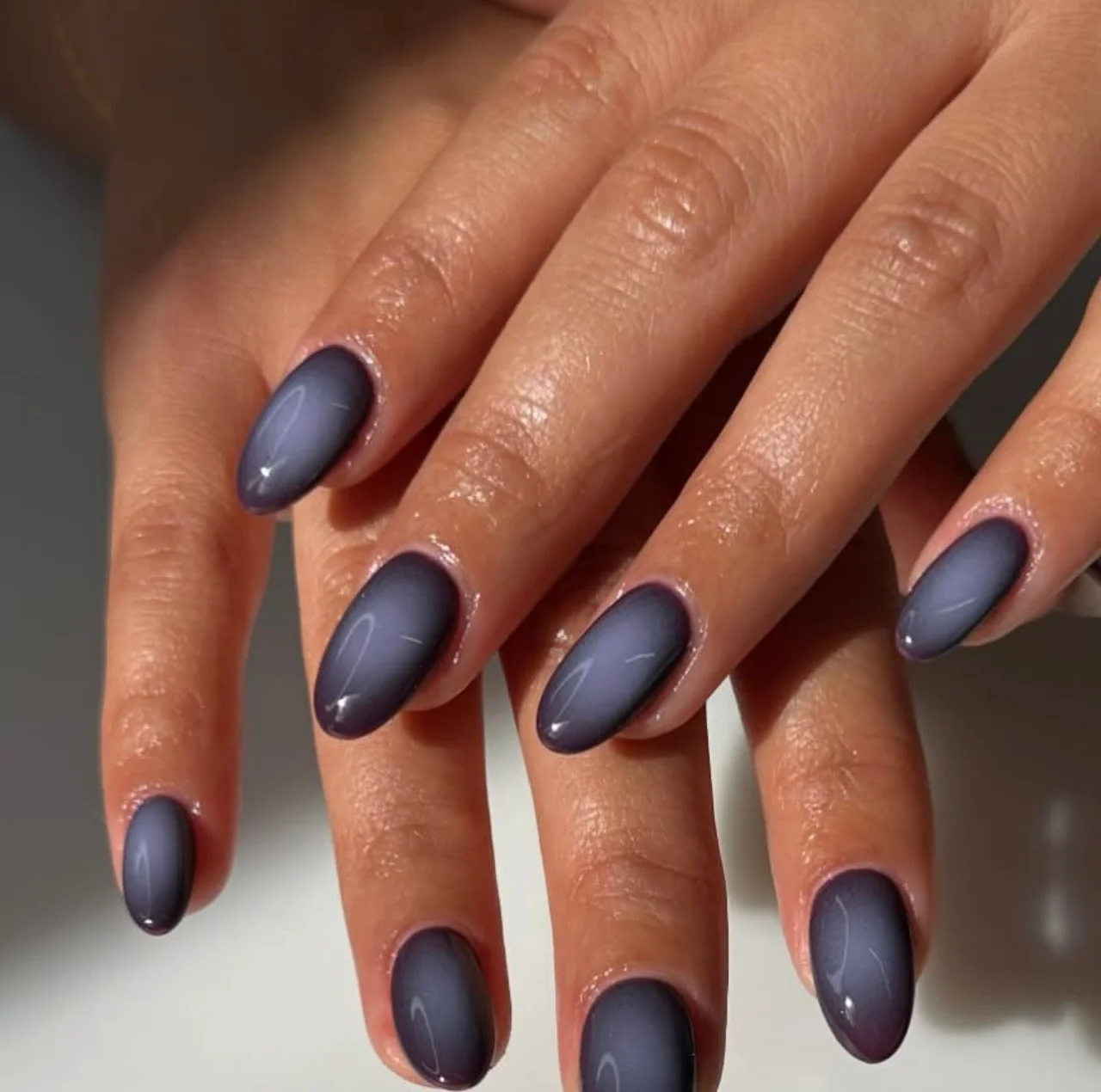 Diseño de uñas efecto aura ciruela en tonos morados.