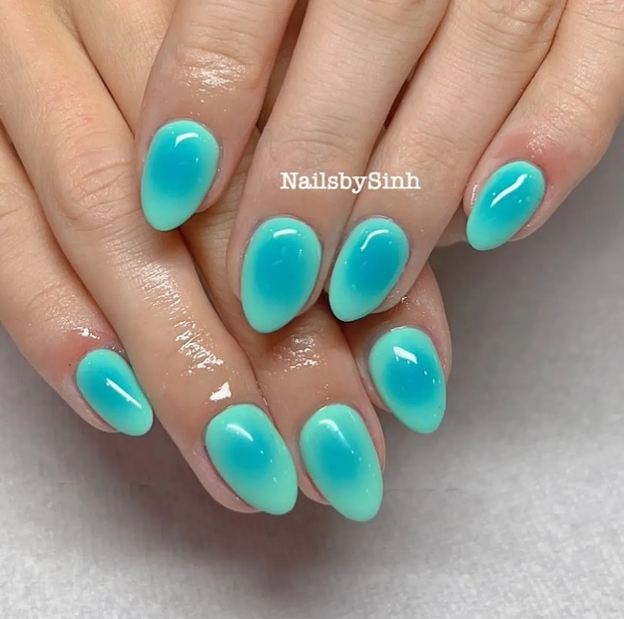 Diseño de uñas efecto aura turquesa con acabado brillante y estilo moderno.