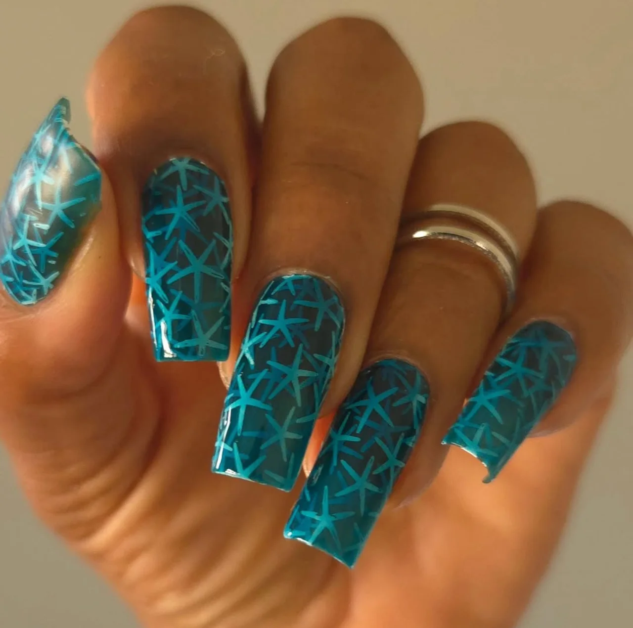 Diseño de uñas estampado en tonos azules con figuras geométricas.