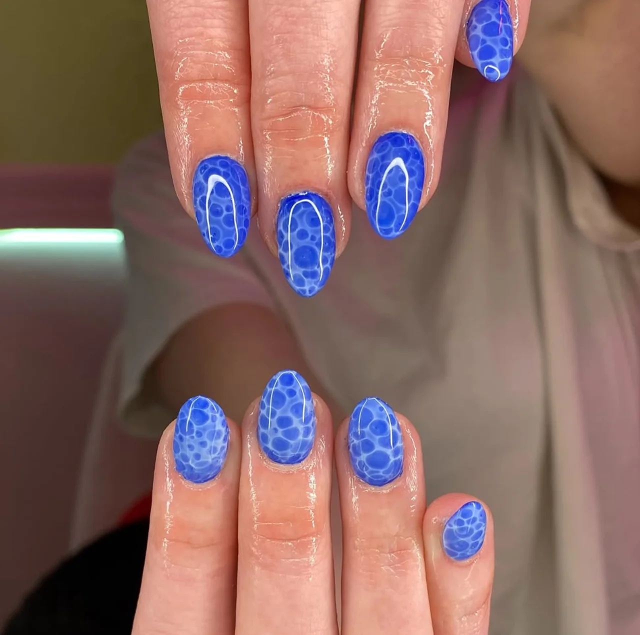Diseño de uñas marmoleado en agua con efecto azul vibrante.