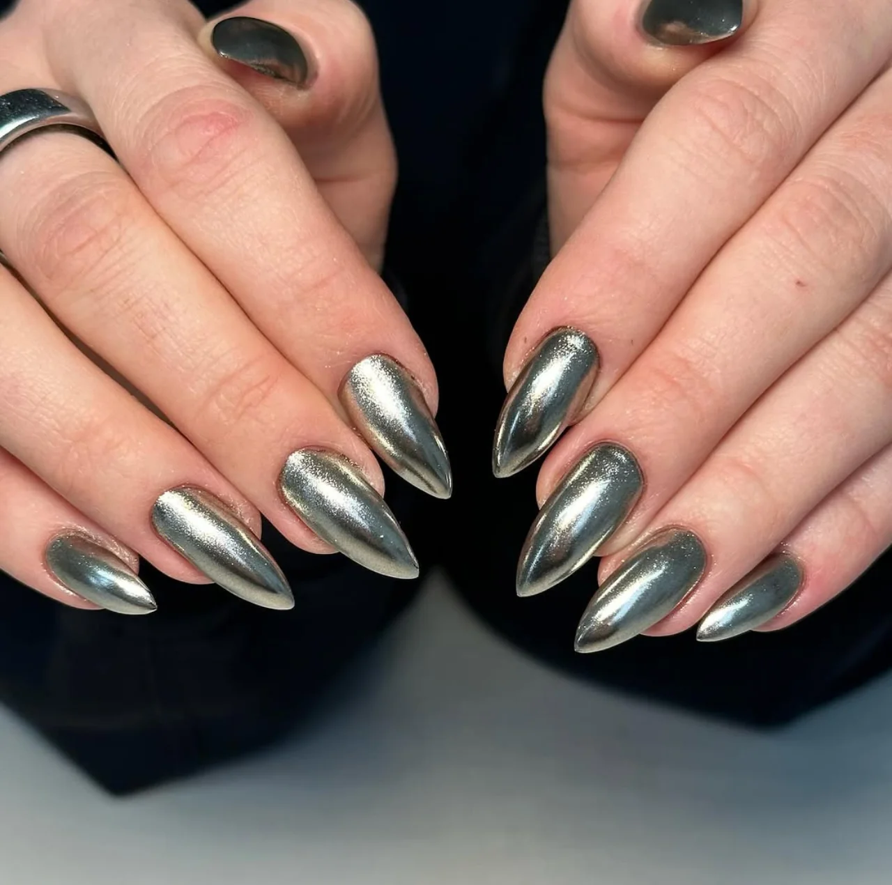 Diseño de uñas metálicas en tono plateado con acabado brillante y forma stiletto.