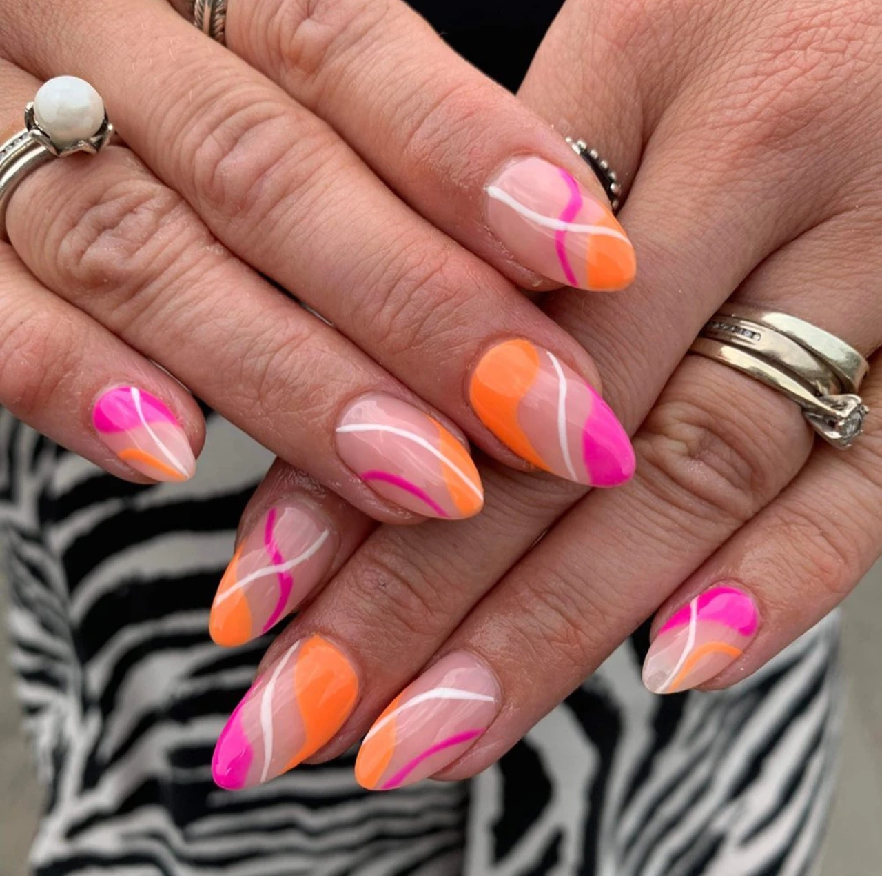 Diseños de uñas acrílicas abstractas neón en tonos rosa, naranja y blanco.