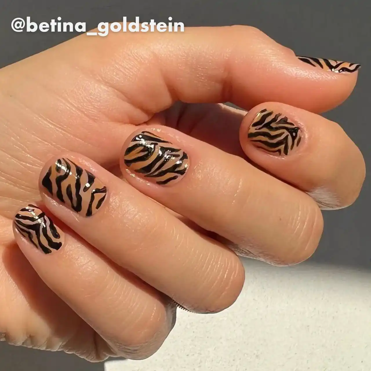 Diseños de uñas acrílicas animal print con estampado de cebra en tonos nude y negro.