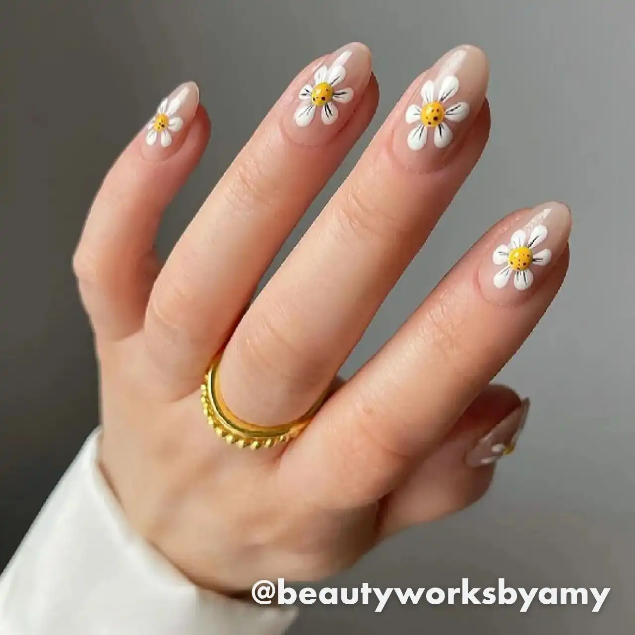 Diseños de uñas acrílicas florales con margaritas en base nude.