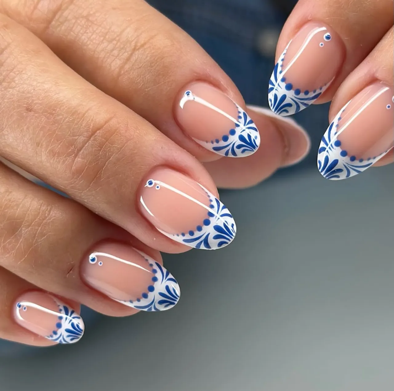 Diseños de uñas acrílicas francesas en blanco y azul con decoración floral y puntos simétricos.