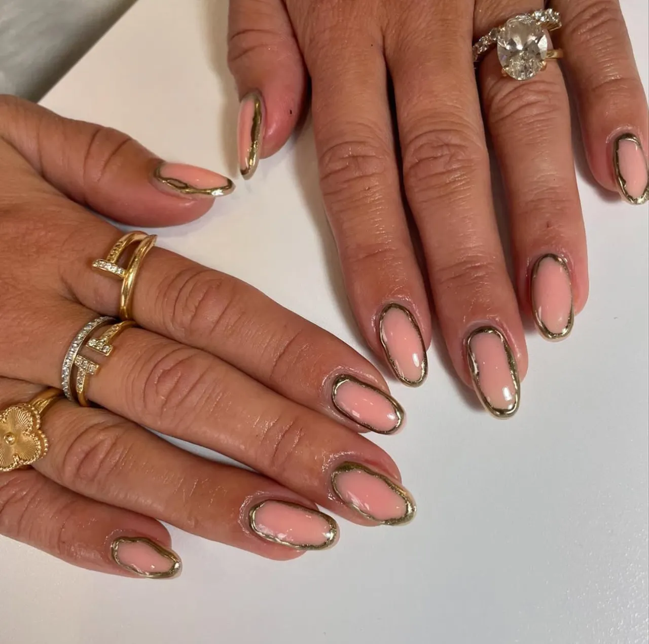 Diseños de uñas acrílicas francesas con borde dorado metálico sobre base nude.