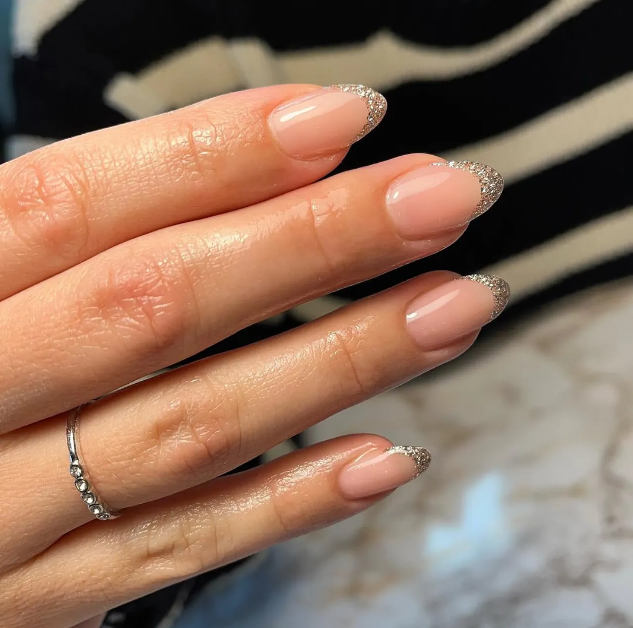 Diseños de uñas acrílicas francesas con glitter plateado en punta almendrada.