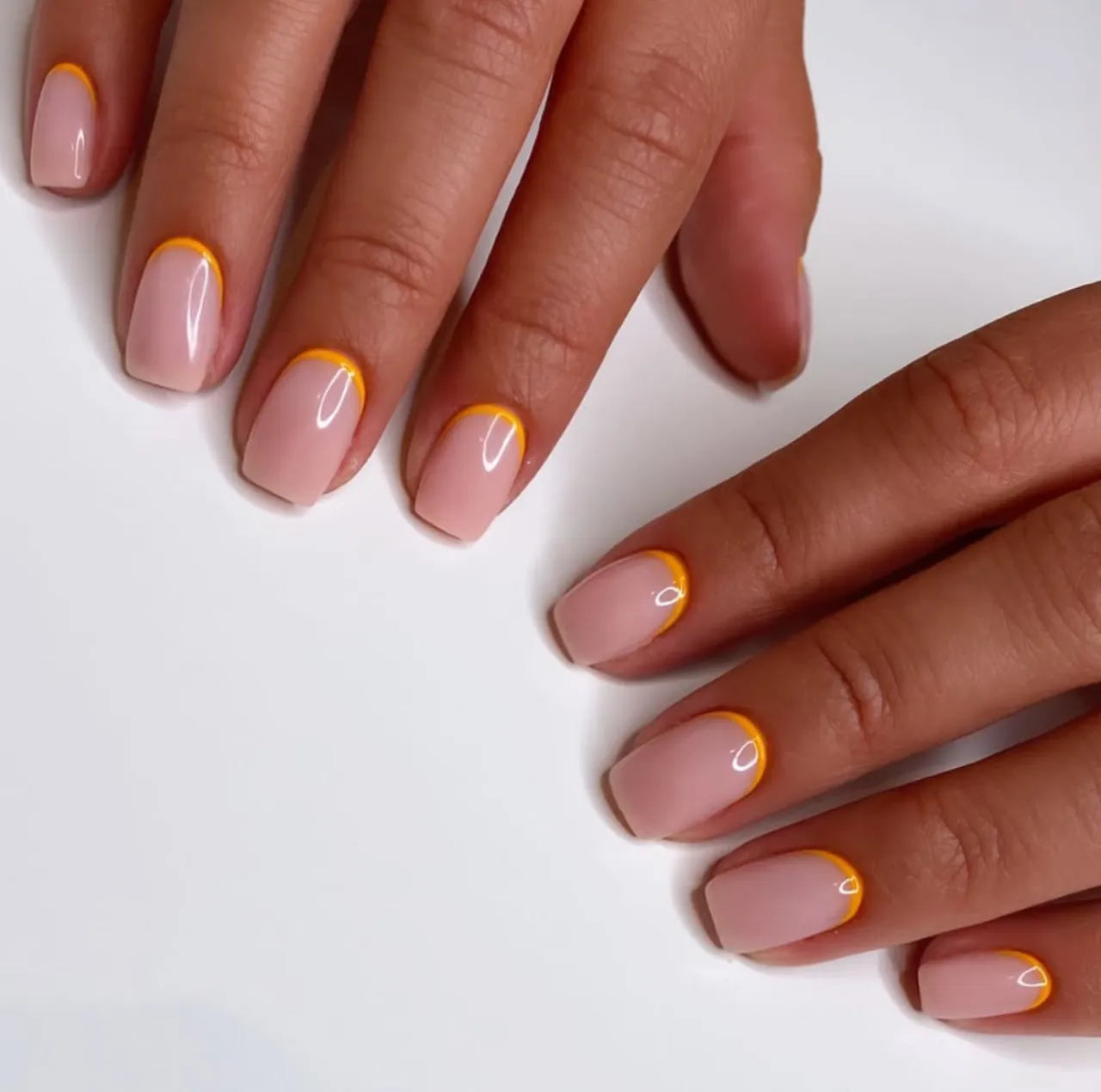 Diseños de uñas acrílicas francesas de colores invertidas con borde naranja vibrante.