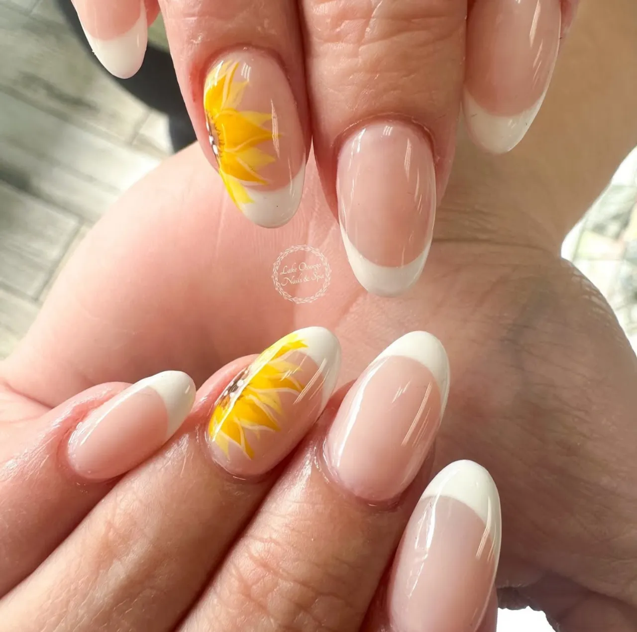 Diseños de uñas acrílicas francesas con girasoles pintados a mano sobre base nude.