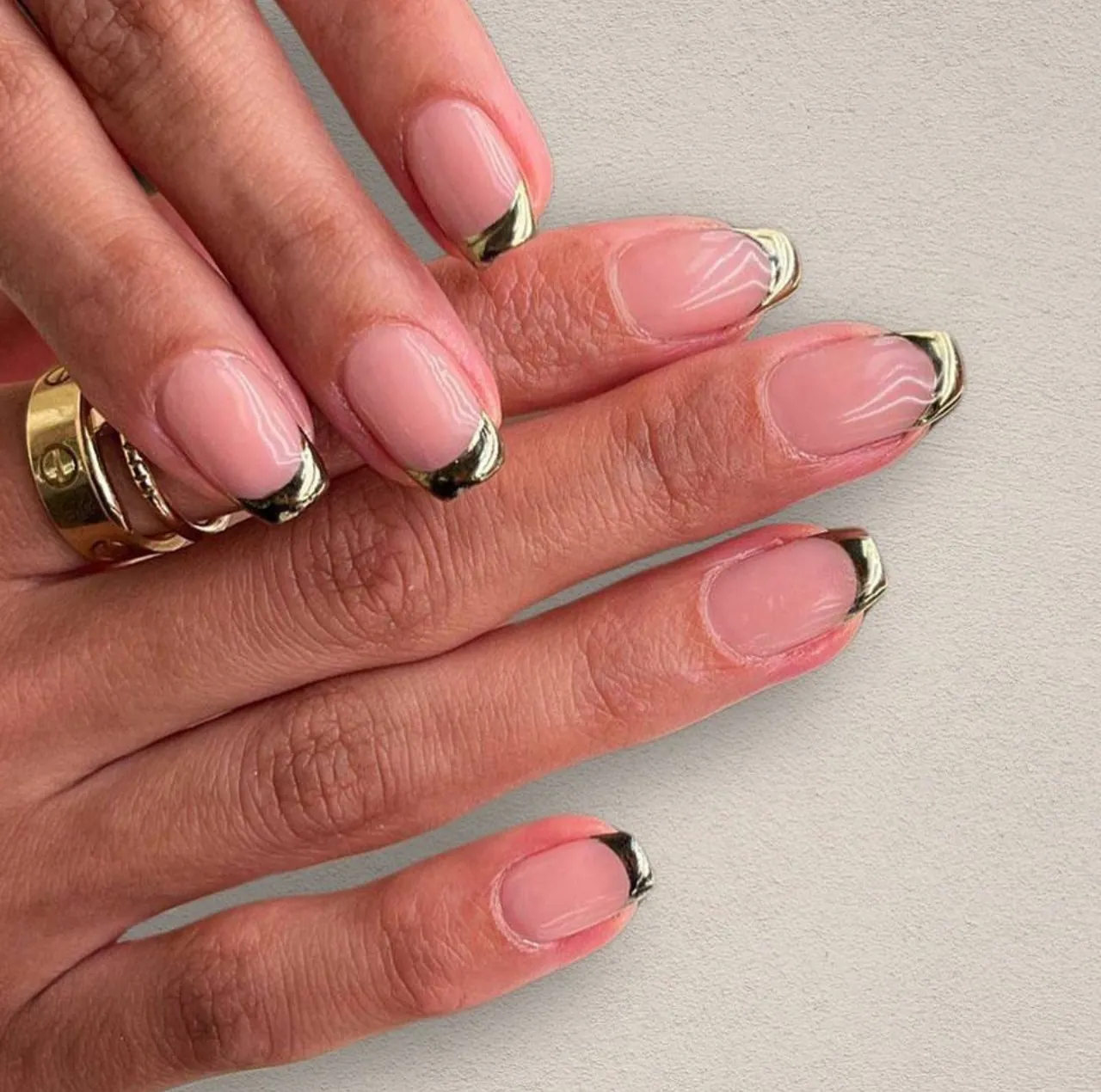 Diseños de uñas acrílicas francesas doradas metalizadas con base nude y acabado elegante.