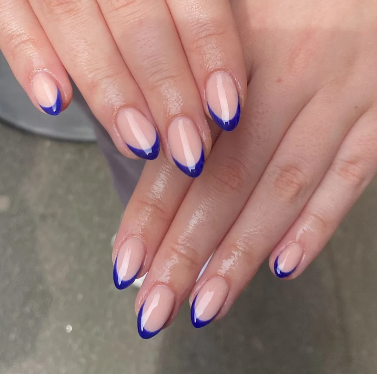 Diseños de uñas acrílicas francesas con patrón azul en forma almendrada.