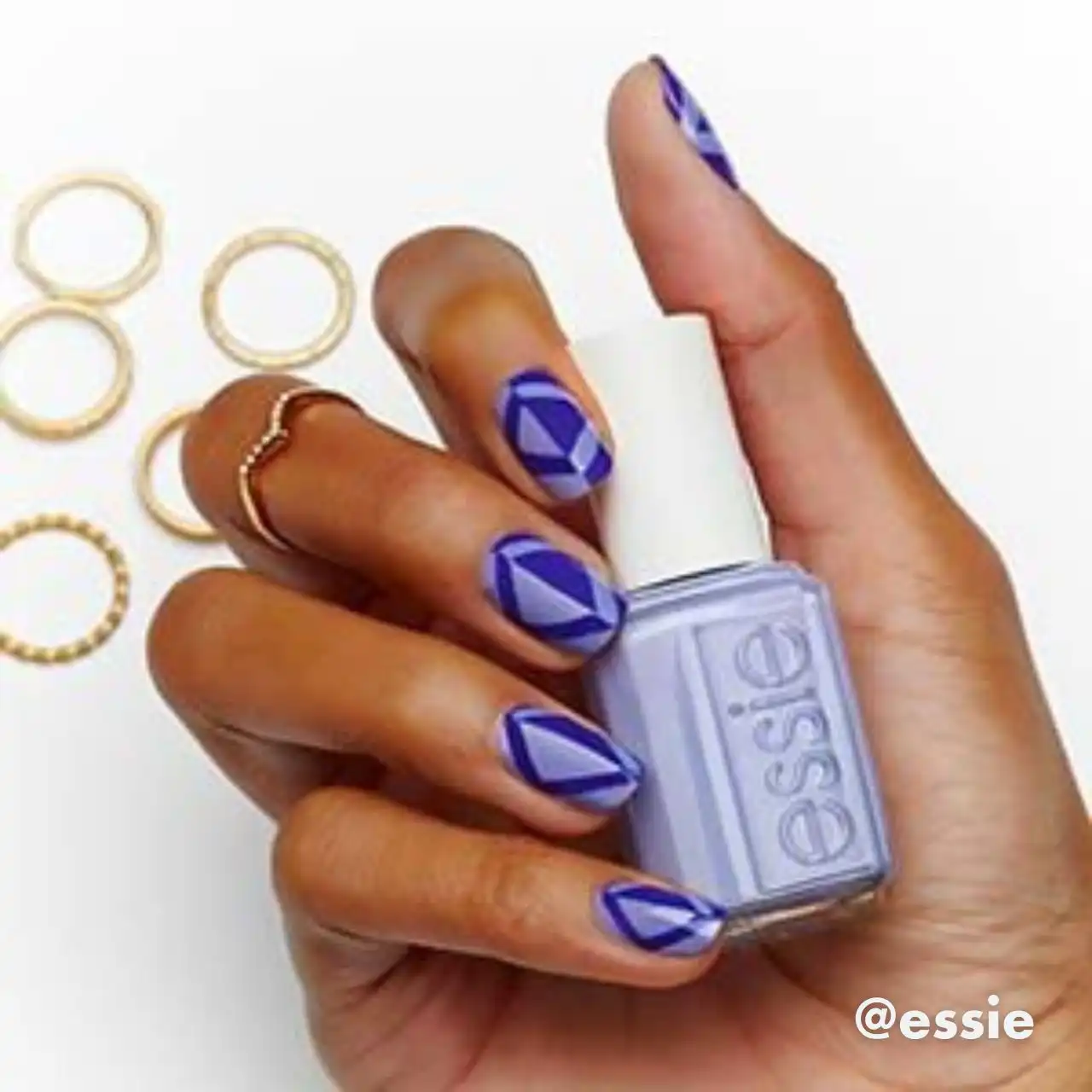 Diseños de uñas acrílicas geométricas en tonos morados con esmalte Essie