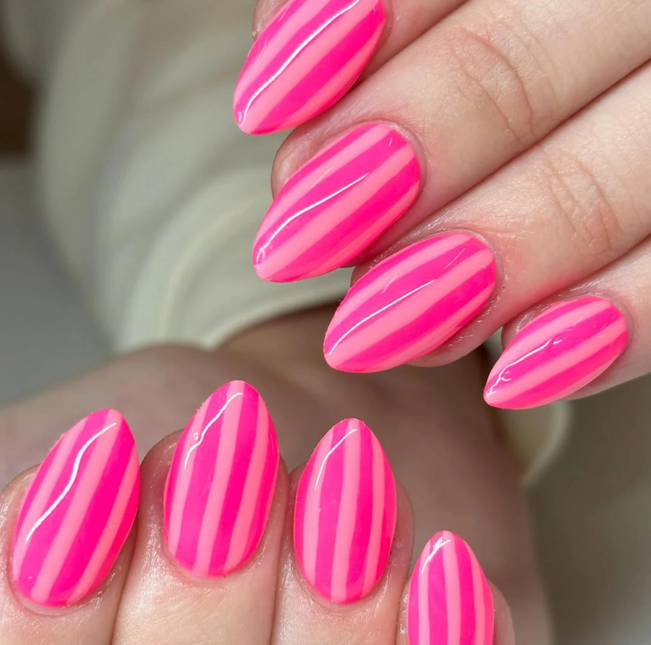 Diseños de uñas acrílicas groovy rosa con líneas verticales en tonos fucsia y neón.