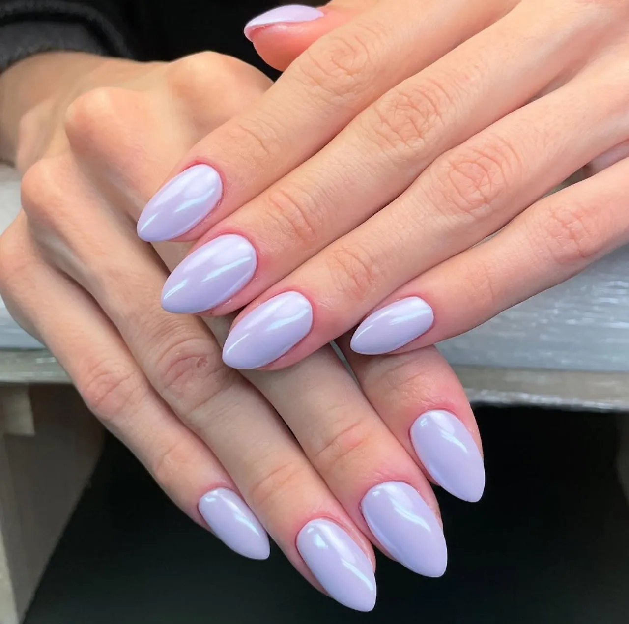 Diseños de uñas acrílicas lilas tradicionales con forma almendrada y acabado brillante.