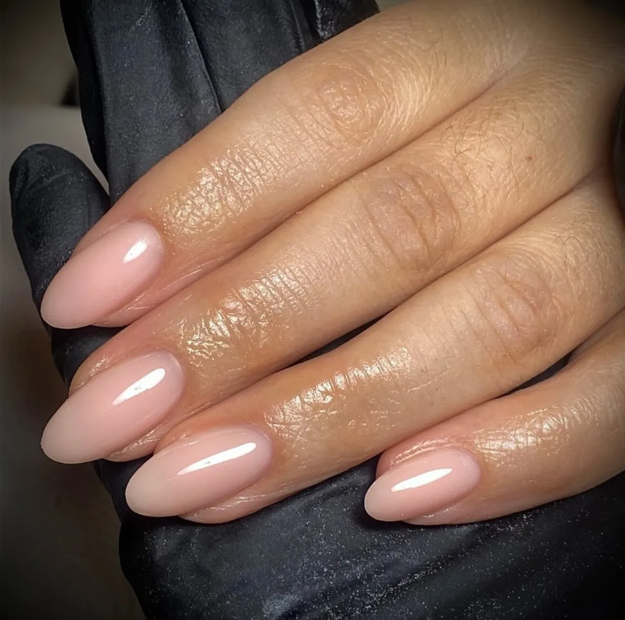 Diseños de uñas acrílicas nude naturales con forma almendrada y acabado brillante.